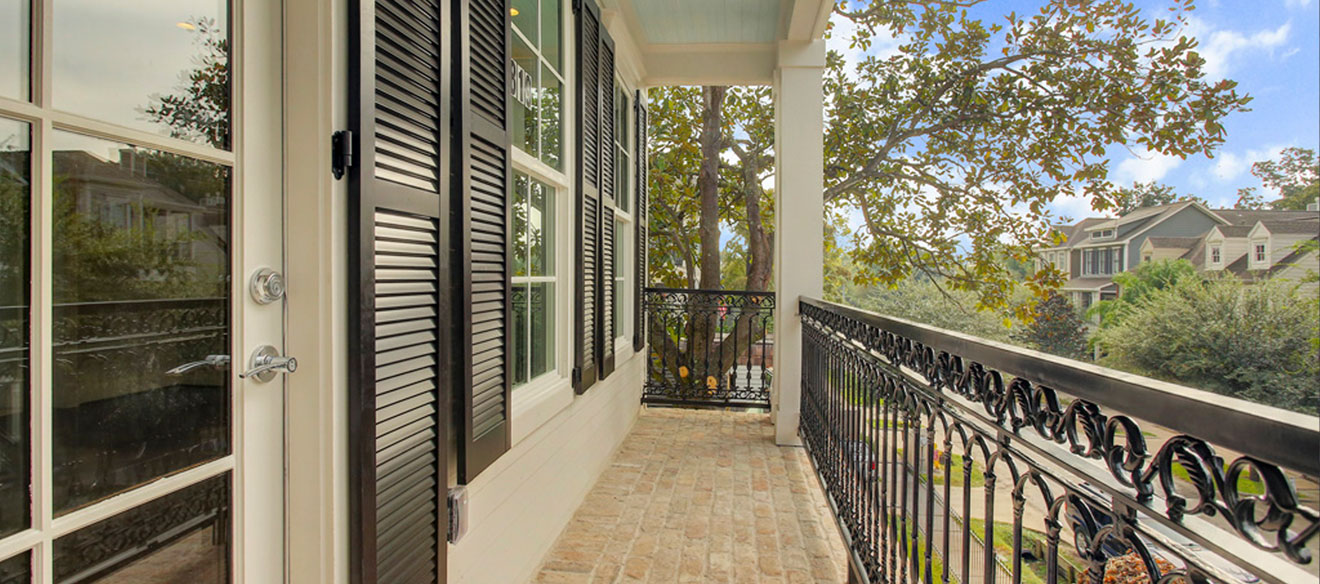 Second story balcony view of a Houston neighborhood. Black iron railing.